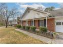 Traditional brick home with a covered porch, trimmed bushes, and an attached two-car garage at 3261 Hidden Forest Dr, Snellville, GA 30078