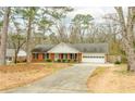 Inviting single-story brick home with mature trees and a long driveway leading to the attached garage at 3261 Hidden Forest Dr, Snellville, GA 30078