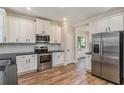 Modern kitchen with stainless steel appliances, white cabinets, and hardwood floors at 1511 New Hope Rd, Locust Grove, GA 30248