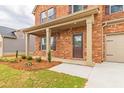 Covered front porch with brick columns, neutral door, and landscaped flower bed at 300 Bianca Way, Mcdonough, GA 30253