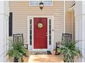 Inviting front door with a decorative wreath, rocking chairs, and potted plants at 308 Helena Pl, Mcdonough, GA 30252