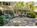 Inviting front entry featuring stone patio with outdoor seating surrounded by lush landscaping and mature trees at 4696 Dunover Cir, Dunwoody, GA 30360