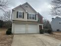 View of the home's two-car garage and neutral siding, complemented by a manicured front yard at 875 Under Ct, Sugar Hill, GA 30518