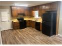 Cozy kitchen with wood cabinets, black appliances, and vinyl flooring at 5790 Northspring Dr, Ellenwood, GA 30294