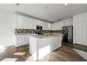 Bright kitchen with white cabinets, granite countertops, mosaic backsplash, and stainless-steel appliances at 1183 Lanier Springs Dr, Buford, GA 30518