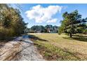 Wide shot of the property showing the dirt driveway and the home with large front yard at 1515 Ozora Rd, Loganville, GA 30052