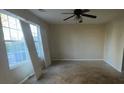 Bright living room with large windows, ceiling fan, and neutral walls at 304 Klinetop Dr, Mcdonough, GA 30253