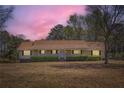 Ranch style home with a long porch and mature trees at twilight at 12142 Panhandle Rd, Hampton, GA 30228