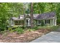 Charming, light green home with a welcoming front porch surrounded by mature trees and natural landscaping at 90 Lakeside Dr, Hiram, GA 30141