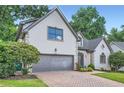 Charming home featuring a two-car garage, brick driveway, and lush green landscaping at 140 Grosvenor Pl, Atlanta, GA 30328
