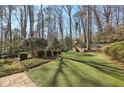 Spacious backyard featuring artificial turf, mature trees, landscaping and a wooden playset at 3902 Sheldon Ne Dr, Atlanta, GA 30342