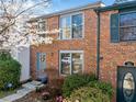 Brick-front townhome with charming curb appeal showcasing a decorative door wreath and blossoming spring foliage at 288 Roswell Commons Cir, Roswell, GA 30076