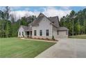 Well-manicured lawn of a home with an attached two-car garage and long driveway, showing classic design at 31 Homesite Cooper E Cv, Fayetteville, GA 30214