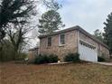 Brick home with a garage, surrounded by greenery, offering a blend of comfort and practicality at 676 Bralorne Dr, Stone Mountain, GA 30087
