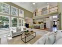 Bright living room with soaring ceilings, large windows and a view into the modern kitchen at 10860 Donamere Dr, Johns Creek, GA 30022