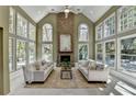 Sun-drenched living room featuring a stone fireplace, soaring ceilings, and walls of windows at 10860 Donamere Dr, Johns Creek, GA 30022