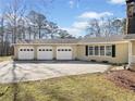 Side view of a home with a three-car garage with an expansive driveway and beautifully maintained lawn at 444 Pineview Dr, Canton, GA 30114