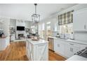 Open kitchen featuring white cabinetry, stainless steel appliances, hardwood floors, island and eat-in area at 3975 River Club Dr, Cumming, GA 30041