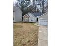 Single-story home with stone accents, gray vinyl siding, two-car garage, and mature trees at 2071 Boone Pl, Snellville, GA 30078
