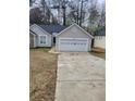 Single-story house featuring gray vinyl siding, a two-car garage, and a long concrete driveway at 2071 Boone Pl, Snellville, GA 30078