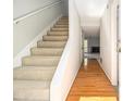 Hallway featuring a staircase with carpeted steps and a hardwood floor that leads to the front door at 6437 Stone Way, Morrow, GA 30260