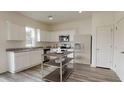 Modern kitchen with white cabinets, stainless steel appliances, kitchen island, and granite countertops at 7728 Sudbury Cir, Covington, GA 30014