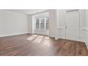 Bright room featuring hardwood floors, three windows bringing in light, white walls, and a white front door at 3130 Caney Creek Ln, Cumming, GA 30041