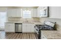 Bright kitchen featuring granite countertops, stainless steel appliances, and white cabinetry at 1908 Sailcloth St, Lithonia, GA 30058