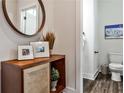 Stylish powder room with wood-look flooring, wood cabinet, round mirror, and modern fixtures at 4454 Dandelion Ln, Atlanta, GA 30342