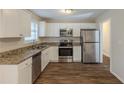 Modern kitchen featuring stainless steel appliances, granite countertops, white cabinets, and wood floors at 1526 Colony East Cir, Stone Mountain, GA 30083