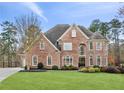 Beautiful two-story brick home featuring a manicured lawn, mature trees, and elegant architectural details at 2601 Floral Valley Dr, Dacula, GA 30019