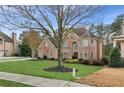 Charming two-story brick home with lush green lawn, mature trees, and elegant architectural details at 2601 Floral Valley Dr, Dacula, GA 30019
