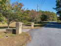 Brick entrance pillars, set on a paved road lined with trees, offer a welcoming start to the property at 8736 Camp Rd, Winston, GA 30187