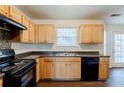Kitchen with wood cabinets, black appliances, and dark countertops at 445 Skif Pond Ct, Atlanta, GA 30349