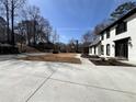 Long concrete driveway leads to a white two-story home with black trim and large green space at 4960 Trevino Cir, Duluth, GA 30096
