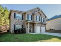 Inviting two-story brick home with black shutters, a two-car garage, and lush front yard at 2154 Dodson Woods Dr, Fairburn, GA 30213