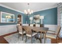 Elegant dining room with modern lighting, wood floors, wainscoting and blue walls at 655 Amberton Close, Suwanee, GA 30024