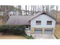 Two-story home featuring a two-car garage, stone accents, and surrounded by lush greenery and mature trees at 326 Rockland Way, Lawrenceville, GA 30046