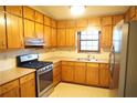 Kitchen featuring natural wood cabinets, laminate countertops, stainless steel appliances, and a window at 326 Rockland Way, Lawrenceville, GA 30046