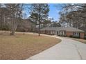 View of brick home on large lot with mature trees and a winding driveway offering plenty of parking at 3003 Hanover Se Ln, Conyers, GA 30094