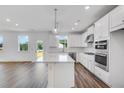 Modern kitchen features white cabinets, stainless steel appliances, a large center island, and hardwood floors at 1466 Auburn Glen Rd, Dacula, GA 30019