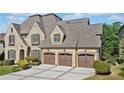 Elegant brick home boasting a three-car garage, dormer windows, and lush green lawn at 1965 Carlotta Ct, Atlanta, GA 30345