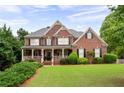 Charming brick home with manicured lawn, covered porch, and lush landscaping at 235 Rippling Nw Dr, Marietta, GA 30064