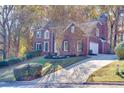 View of the red brick home exterior featuring an attached garage and manicured lawn at 2001 Towne Lake W Hls, Woodstock, GA 30189