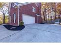 Exterior side view of a brick home featuring the garage and a paved driveway at 2001 Towne Lake W Hls, Woodstock, GA 30189