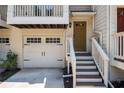 Charming townhome entrance with wooden stairs, a white garage door, and a light fixture above the door at 1537 Liberty Nw Pkwy, Atlanta, GA 30318