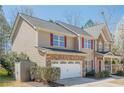 Side view of a beautiful two-story home with stone accents, red shutters, attached garage, and landscaped yard at 9225 Wilshire Pl, Cumming, GA 30028