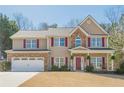 Beautiful two-story home with stone accents, red shutters, an attached garage, and a rocking chair front porch at 9225 Wilshire Pl, Cumming, GA 30028