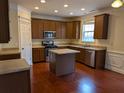 Well-lit kitchen featuring stainless steel appliances, brown cabinets and an island at 735 Briarhurst Ct, Lawrenceville, GA 30046