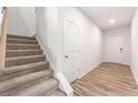 Inviting hallway featuring stairs with carpet, and neutral paint and luxury vinyl flooring at 8523 Poston Place Lot 132, Douglasville, GA 30134